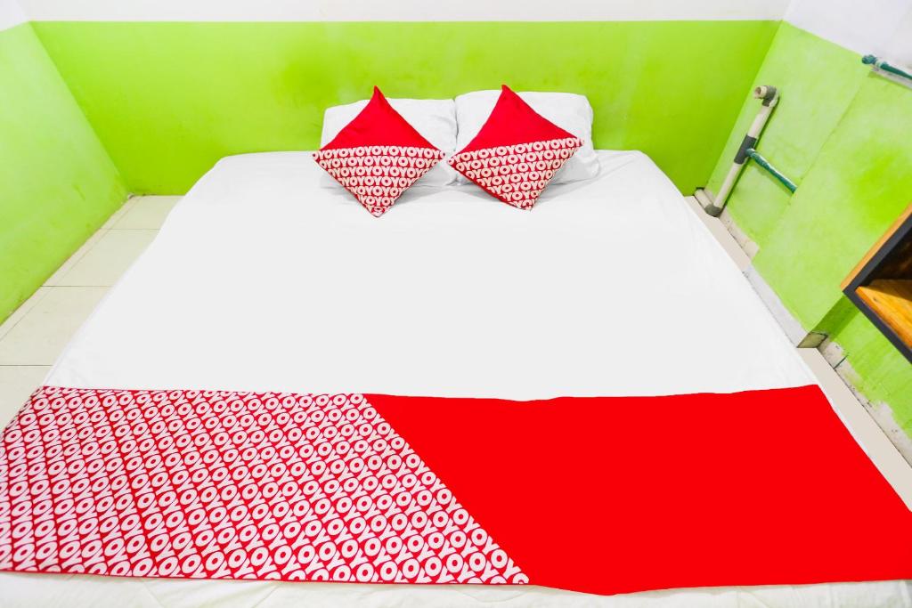 JodohOYO 91344 Wr House Syariah Batam的一张带两个红色和白色枕头的床
