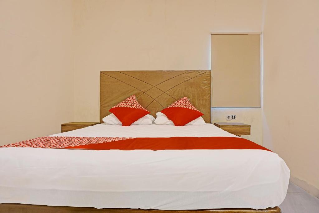 马卡萨Collection O 91414 Hotel Marina Beach的一间卧室配有一张带红色和白色枕头的大床