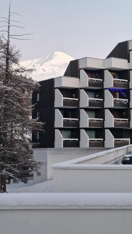 瓦尔"Miramonte" appartement avec terrasse vue montagne et parking privatif sous-sol, à proximité immédiate des pistes, cœur de Vars les Claux, secteur point show avec commodités et piscine chauffée de plein air的公寓大楼的背景是一座白雪覆盖的山
