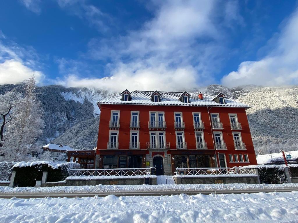 勒布罗伊斯hôtel oberland的雪中一座红色的建筑,背景是群山