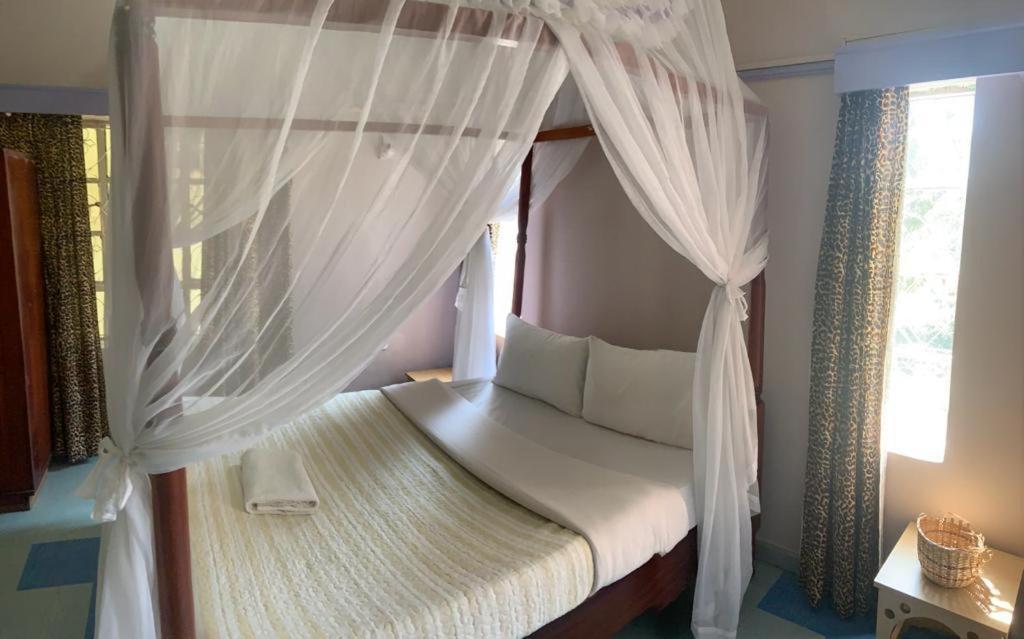 奈瓦沙TAPHE GUEST RESORT的卧室配有带白色窗帘的天蓬床