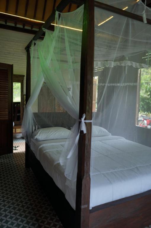 巴图卡拉Villa Embun Batukaras的卧室配有带白色床单的天蓬床