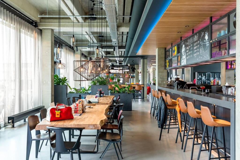 乌得勒支Moxy Utrecht的一间带木桌椅的餐厅和一间酒吧