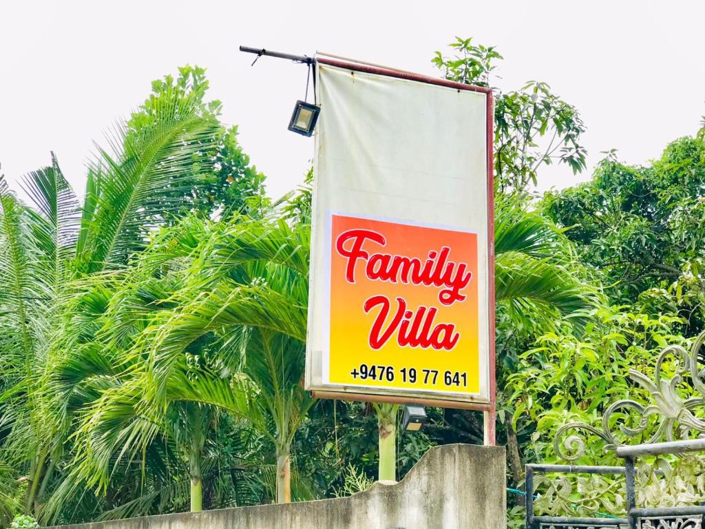 米瑞莎Family Villa Mirissa的树木前的一个家庭村的标志