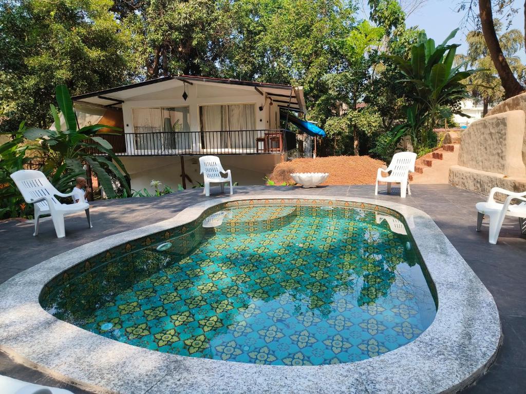 西奥利姆Greek "Jungle Villa", Thalassa Road, Standing alone 3bhk villa with pool的一座带椅子的小游泳池以及一座房子