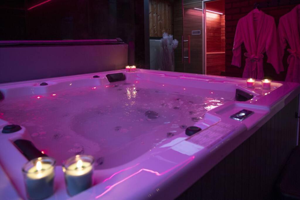 列日SuiteDreams - Bali Suite Liège的浴室内带蜡烛的粉色浴缸