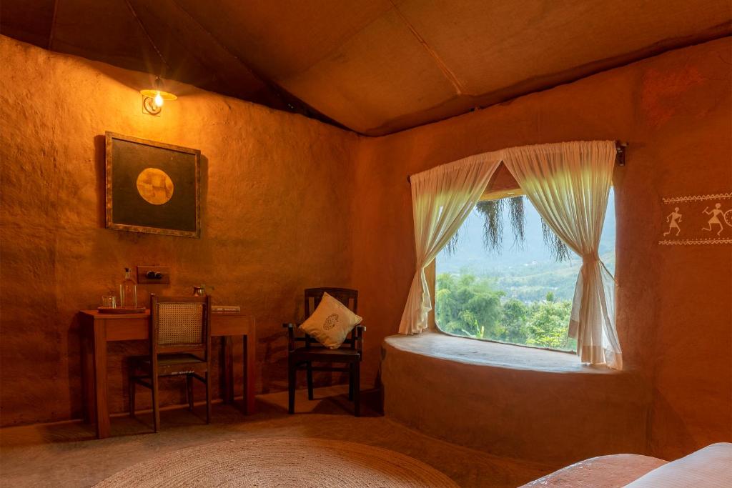 蒙纳The Mudhouse Marayoor的一间卧室设有一张床、一个窗口和一张桌子