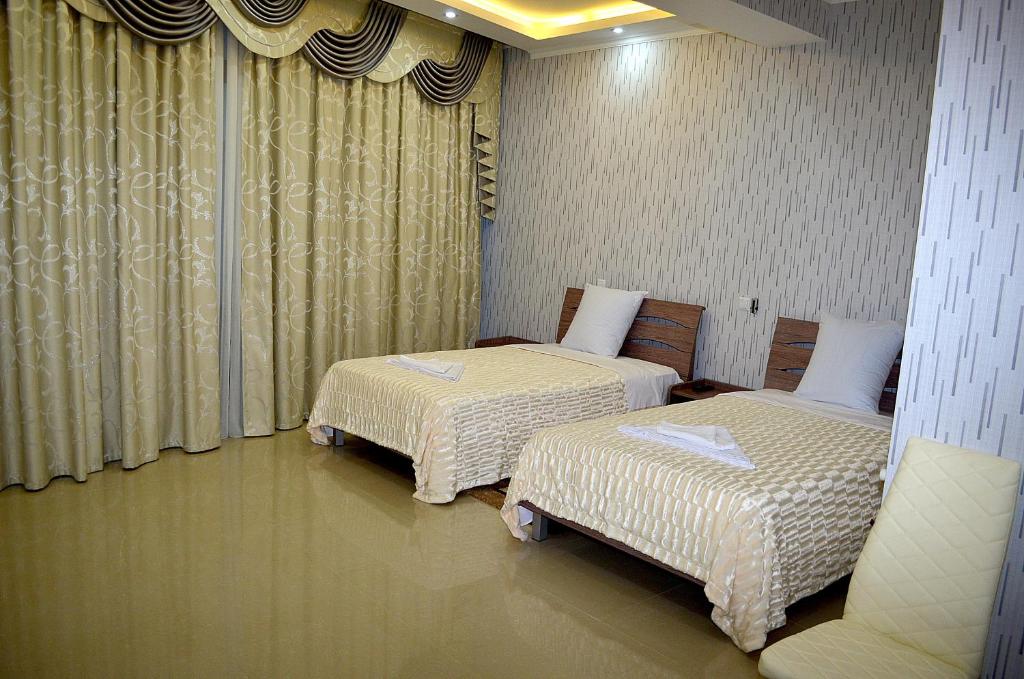 库塔伊西Hotel Okriba的两张床铺,位于带窗帘的房间