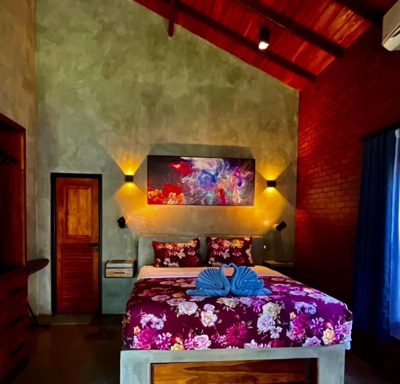 尼甘布Negombo Morawala Beach Villa的一间卧室配有一张紫色床,墙上挂有绘画作品