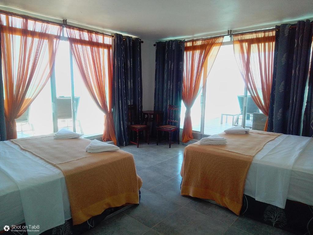 南威游戏鱼旅馆的带大窗户的客房内的两张床