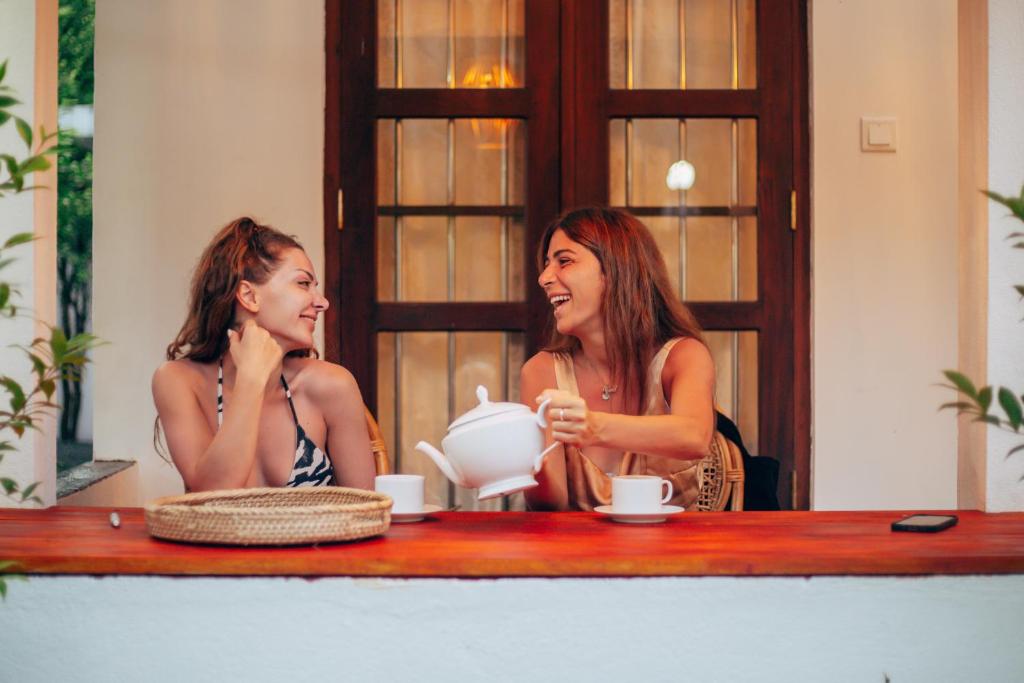 米瑞莎Prasith’s Place的两个女人坐在桌子边,茶壶
