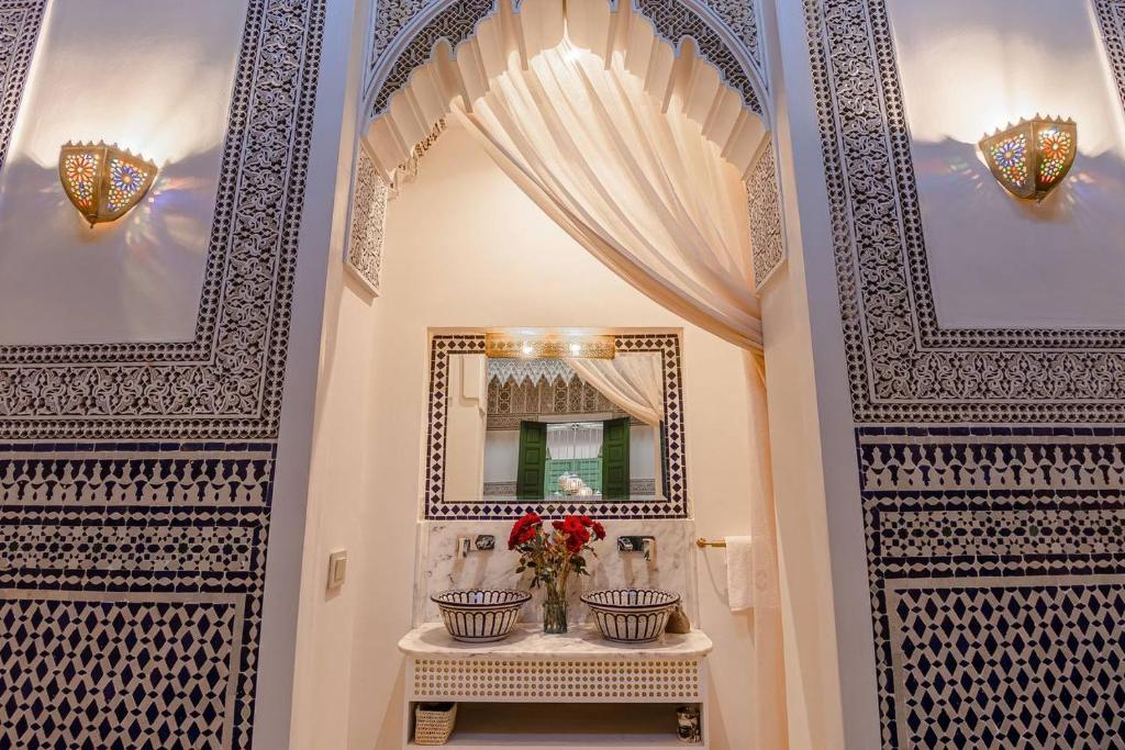 马拉喀什Riad contessa的走廊上设有两扇门,带镜子和鲜花