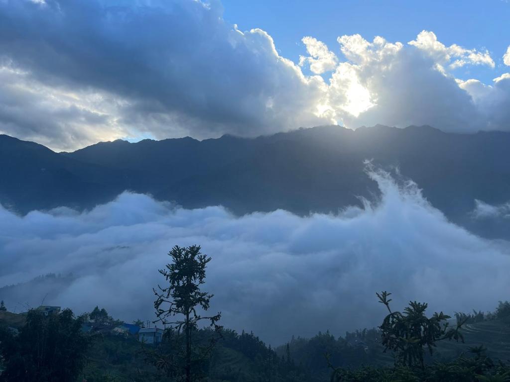 萨帕Sapa Valley view hotel的雾 ⁇ 的山,阳光在云中 ⁇ 