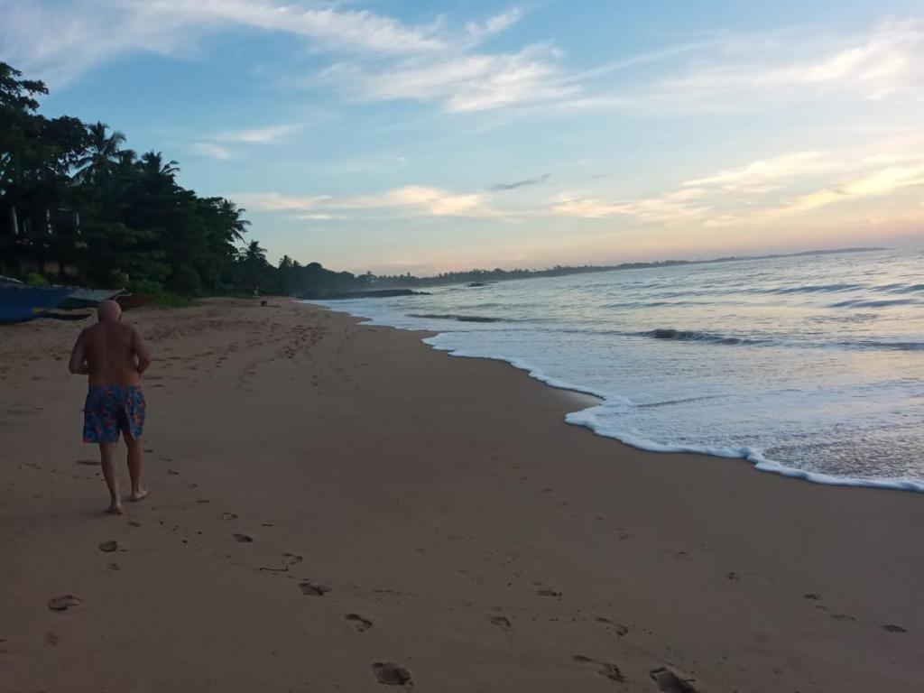 坦加拉Sasagara Beach Villa的一个人在沙滩上行走,脚印在沙滩上