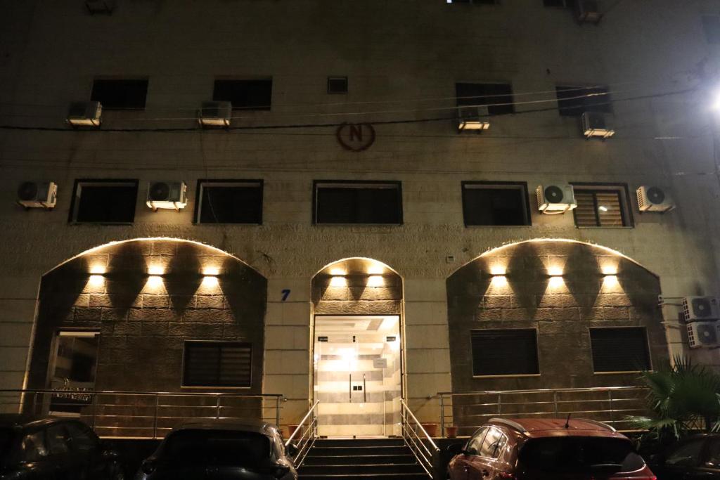 安曼Nour Hotel的前方有两扇门和两辆车的建筑