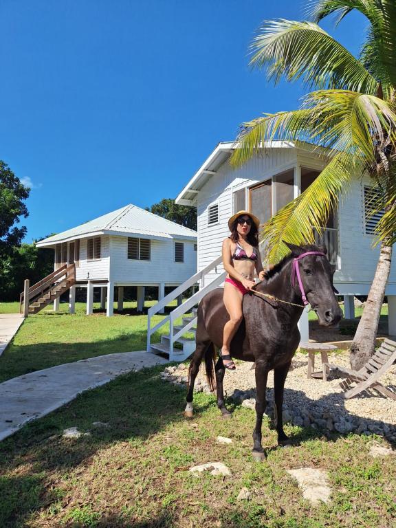 SartenejaHorse Cottage的一位比基尼族的女人在房子前骑马