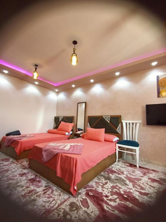 曼苏拉A 5-star hotel room in front of Mansoura University的一间卧室配有一张红色的大床和一把椅子