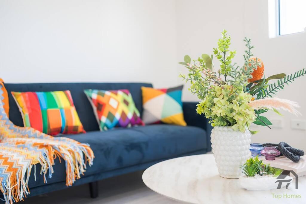 悉尼Entire Home in Lidcombe的客厅配有沙发和带花瓶的桌子