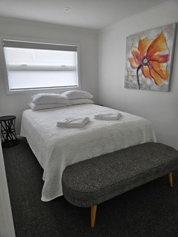 罗托鲁瓦Redwood Apartments的一间卧室设有床、窗户和长凳