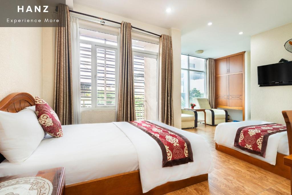胡志明市HANZ Queen Airport Hotel的酒店客房设有两张床和窗户。