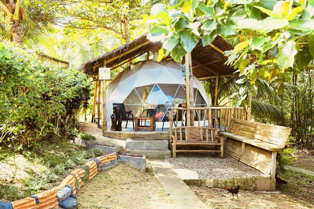 BalilihanEco Glamping Treehouses Closest Resort To All Tourist Attractions的一个带桌子和长凳的帐篷的房子