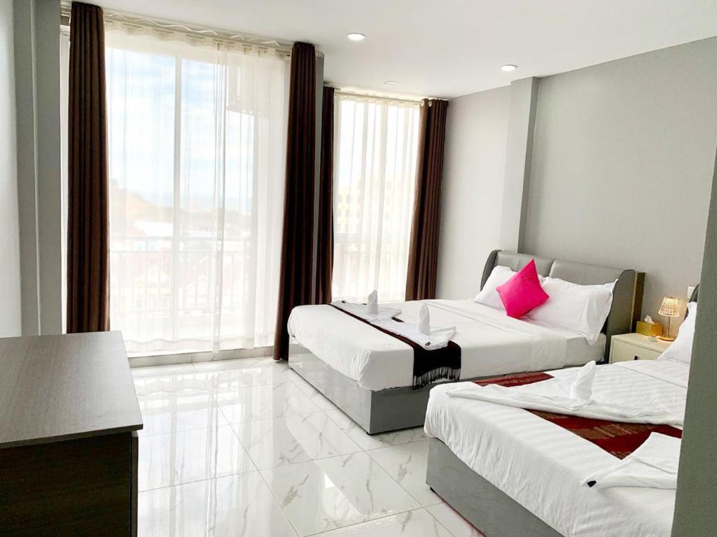 西哈努克Sok Eng Hotel ( សណ្ឋាគារ សុខ អេង )的酒店客房设有两张床和大窗户。