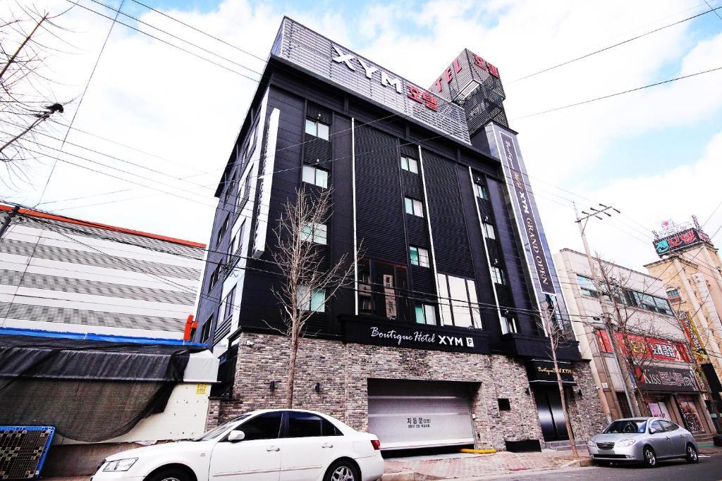 浦项XYM Hotel Mundeok的一座黑色建筑,前面有汽车停放