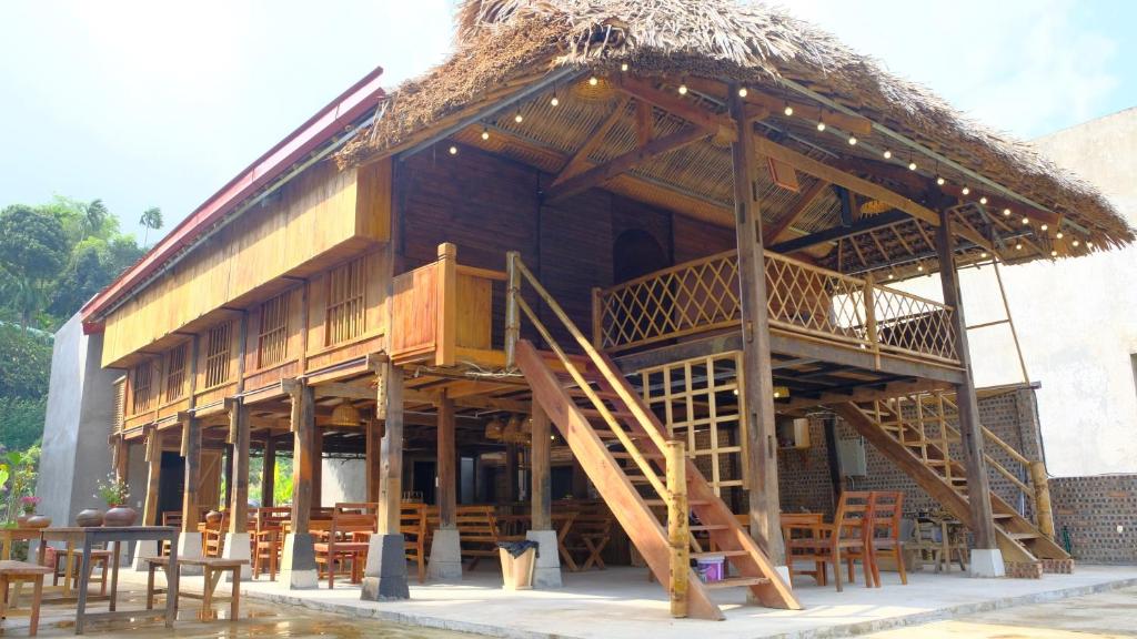河江HÀ GIANG WOODEN HOUSE的一座带桌椅的稻草屋顶建筑