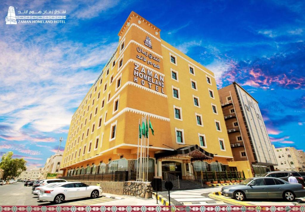 塔伊夫فندق زمان هوم لاند Zaman Homeland Hotel的一座高大的黄色建筑,汽车停在停车场