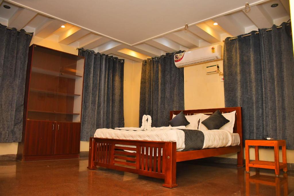 蓬蒂切里Revive Inn Pondy - Rooms & Villa的一间卧室配有带窗帘的木床