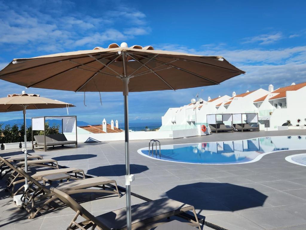 阿德耶Costa Adeje Garden Aparthotel的游泳池旁的天井配有椅子和遮阳伞。