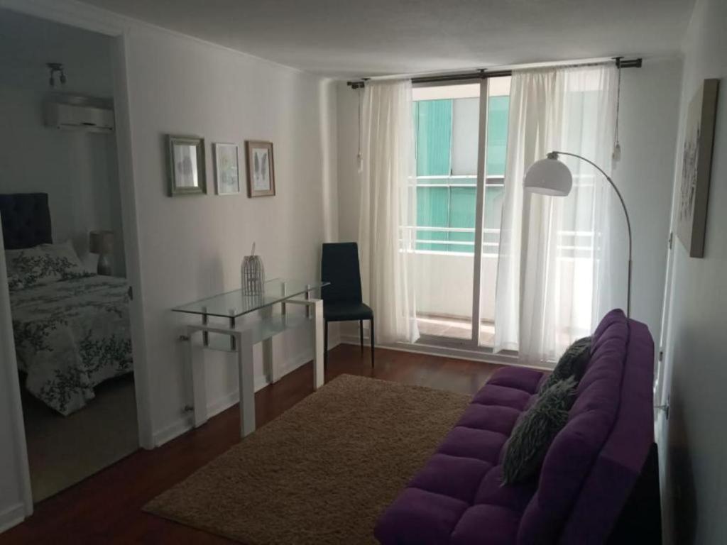 圣地亚哥DEPARTAMENTOS SANTIAGO CENTRO的客厅配有紫色沙发和玻璃桌