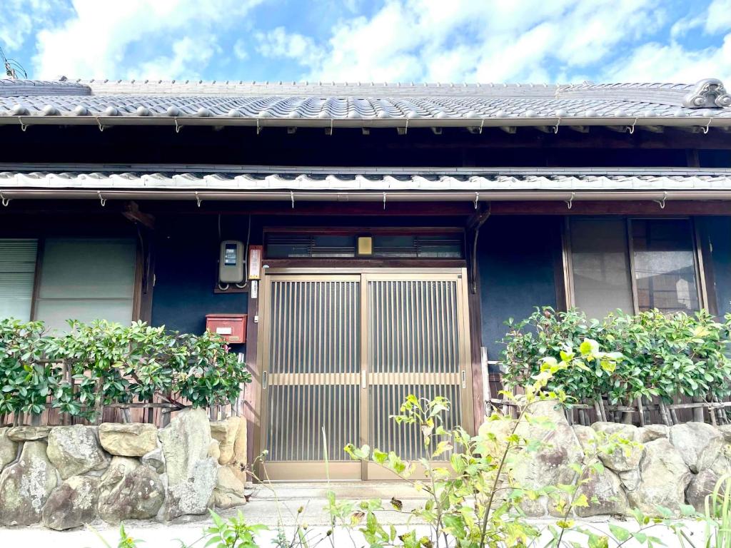 Murotsuギャラリー宿　INNAHOUSE ANDAGALLERY的蓝色的房子,有木门和一些植物