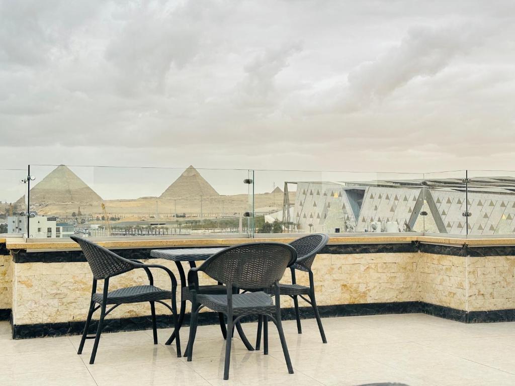 GizaJewel Grand Museum & Pyramids View的屋顶上一张桌子和椅子,上面有金字塔