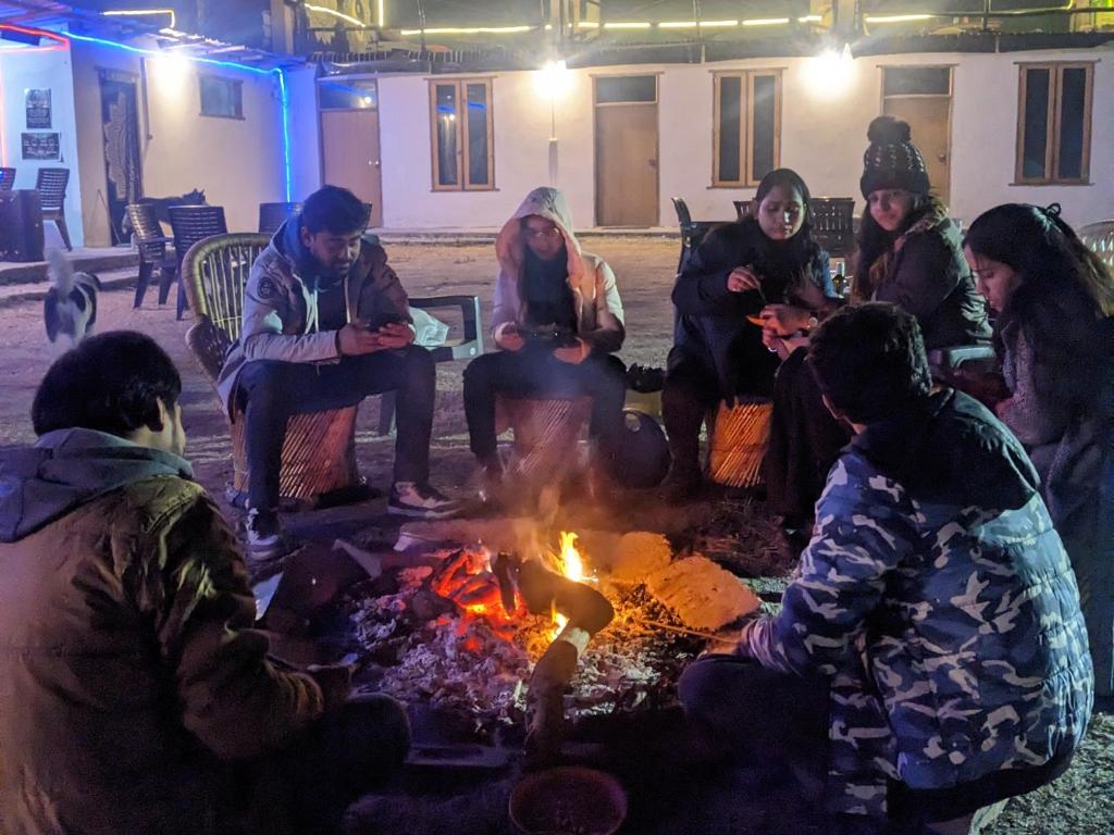 卡索尔Damnbro Cafe & Stay KASOL的一群人围坐在火炉旁