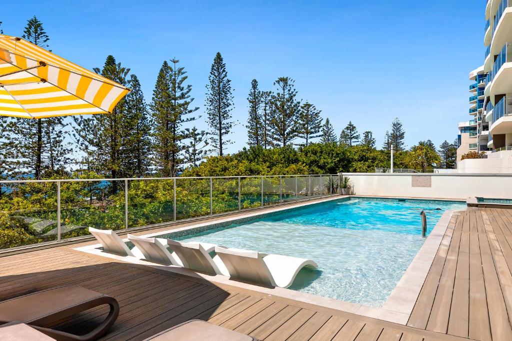 穆卢拉巴太平洋海滩度假酒店的甲板上配有椅子和遮阳伞的游泳池