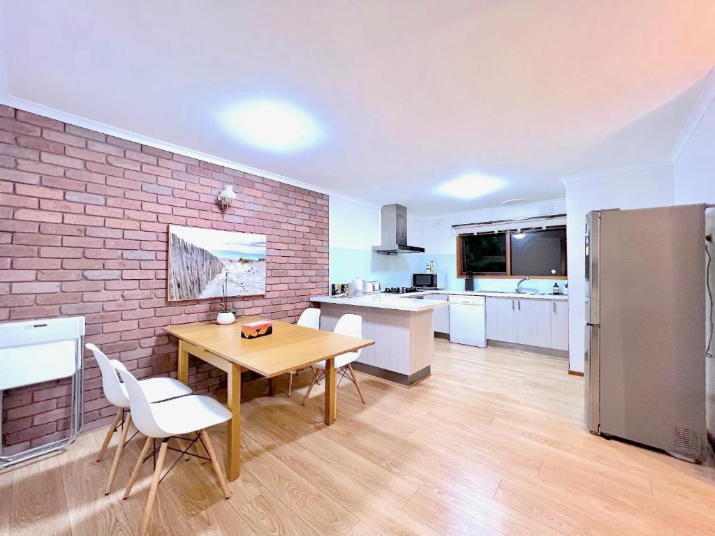 Mount WaverleyBrilliant Modern Flat @Mount Waverley *Smart TV的厨房配有木桌和砖墙