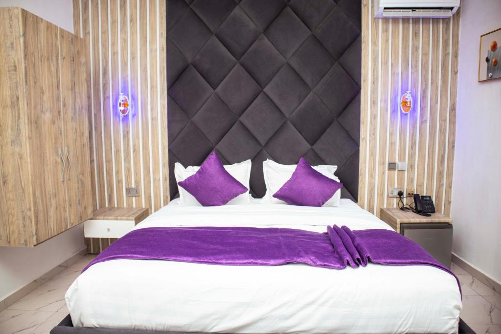 YenagoaLe Rivera Apartments的一间卧室配有一张带紫色枕头的大床
