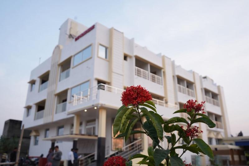 普鲁利耶Swet Palash Resort的前方有红花的白色建筑