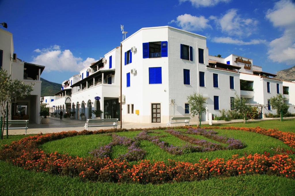 布德瓦亚历山大酒店的一座白色的大建筑,前面有一个花园