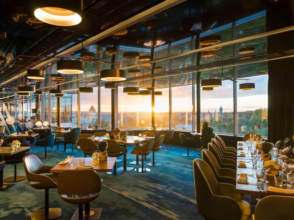 卢森堡索菲特的餐厅设有桌椅和大窗户。