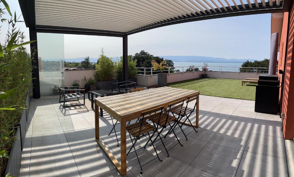 埃维昂莱班IMMODREAMS - L'Attik with lake views and 80m2 terrace的阳台的天井配有桌椅