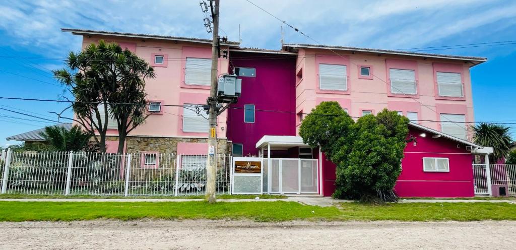 马德普拉塔GRAN HOTEL DE LOS ACANTILADOS的粉红色的房子,前面有栅栏