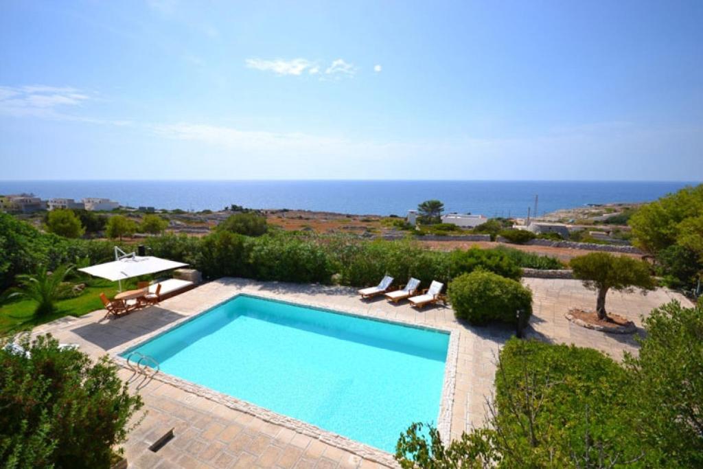 莱乌卡Villa La Pajara的一个带椅子的游泳池,背景是大海