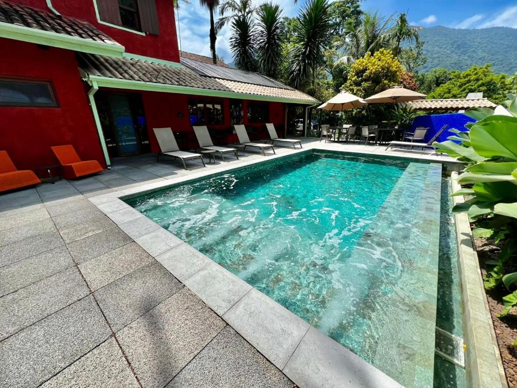 马利西亚斯马利西亚斯庞萨达雷富吉酒店的一个带椅子的游泳池以及一座红色的房子