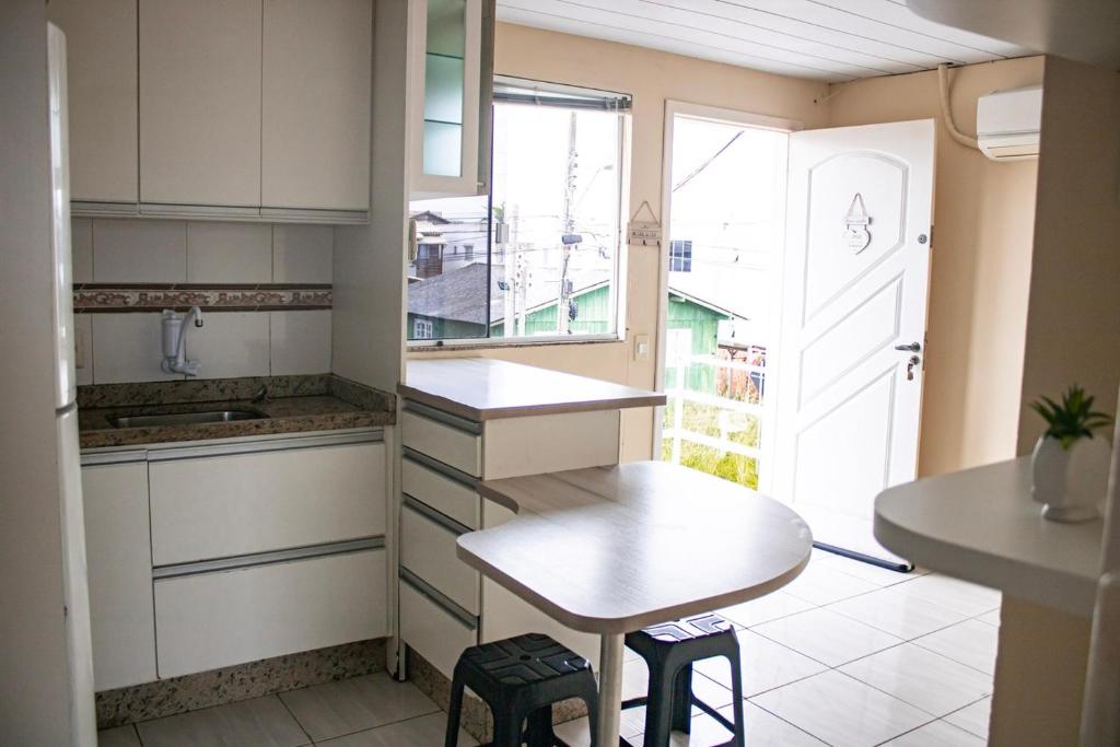 弗洛里亚诺波利斯Otimo apto 9 min do aeroporto em Florianopolis SC的厨房配有桌子和带凳子的小桌子。