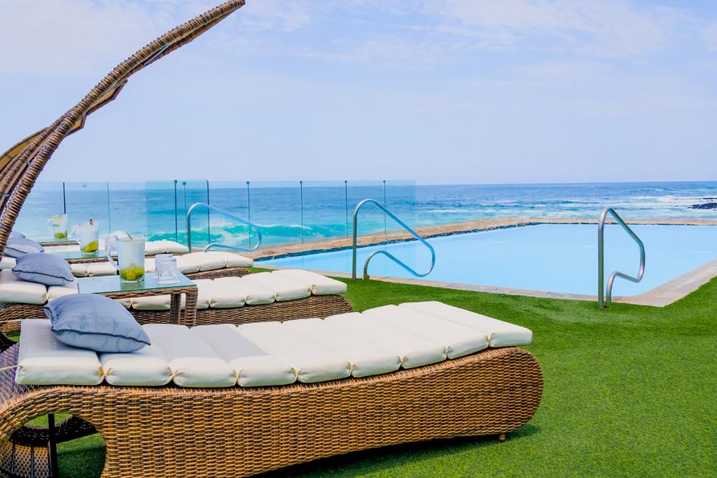 伊基克Hotel Gavina Costa Mar的一组柳条椅和桌子,位于游泳池旁