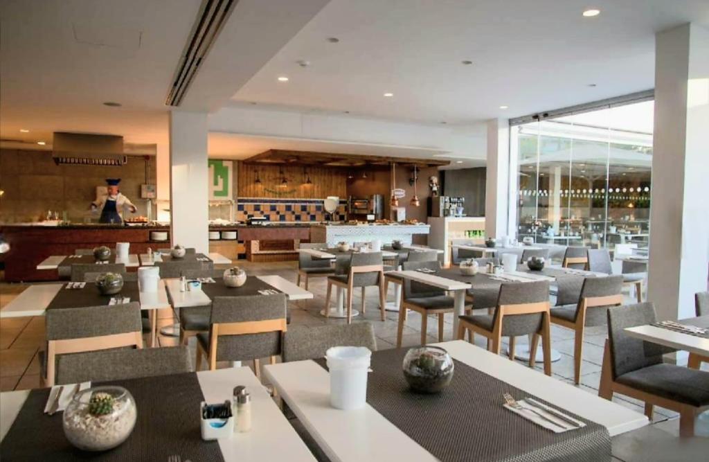 圣巴托洛梅Luxury Apartment Playa del Inglés的餐厅设有桌椅,厨师为背景