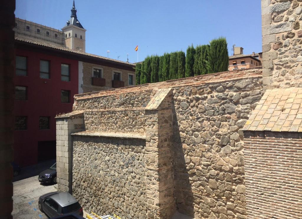 托莱多Alojamiento en el centro de Toledo的旁边设有一堵石头墙,旁边设有一辆汽车