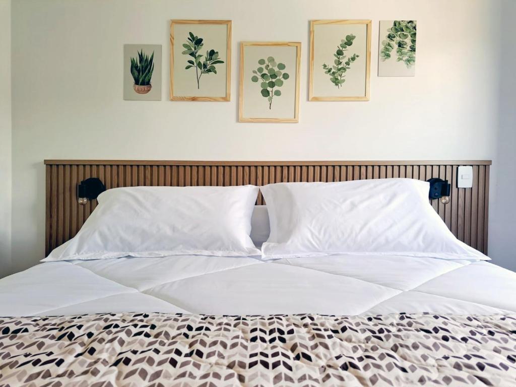 戈亚斯州上帕莱索Casa dos Lírios的卧室配有一张白色床,墙上挂有4张照片